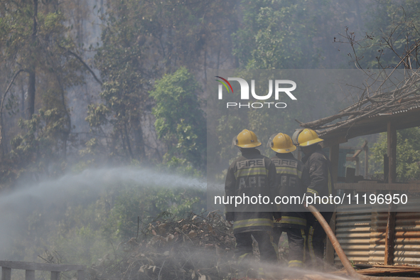 Nepali firefighters are using water cannons to control a blaze that started in a local forest in the Lalitpur District of Central Nepal, on...