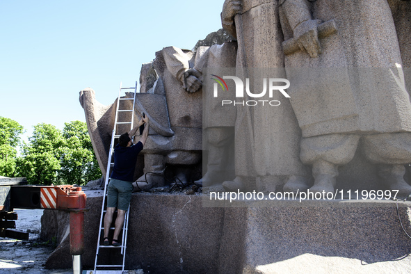 People are taking a photo with dismantled parts of the Soviet monument of friendship between the Ukrainian and Russian peoples in central Ky...