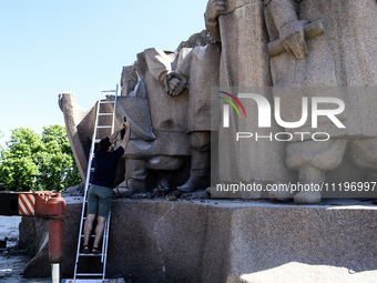 People are taking a photo with dismantled parts of the Soviet monument of friendship between the Ukrainian and Russian peoples in central Ky...