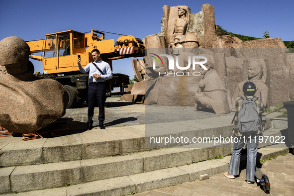 People are taking a photo with dismantled parts of the Soviet monument of friendship between the Ukrainian and Russian peoples in central Ky...