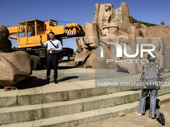 People are taking a photo with dismantled parts of the Soviet monument of friendship between the Ukrainian and Russian peoples in central Ky...