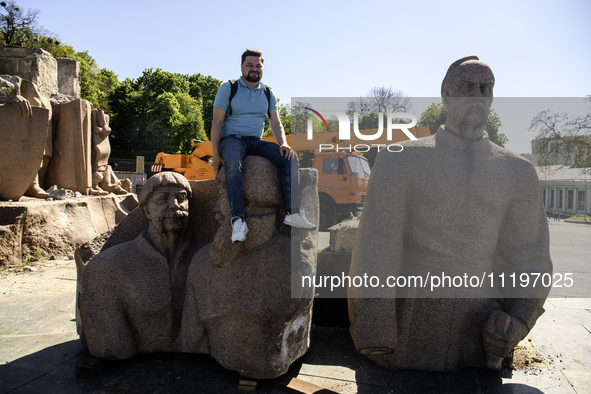 People are taking a photo with dismantled parts of the Soviet monument of friendship between the Ukrainian and Russian peoples in central Ky...