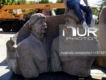 People are taking a photo with dismantled parts of the Soviet monument of friendship between the Ukrainian and Russian peoples in central Ky...