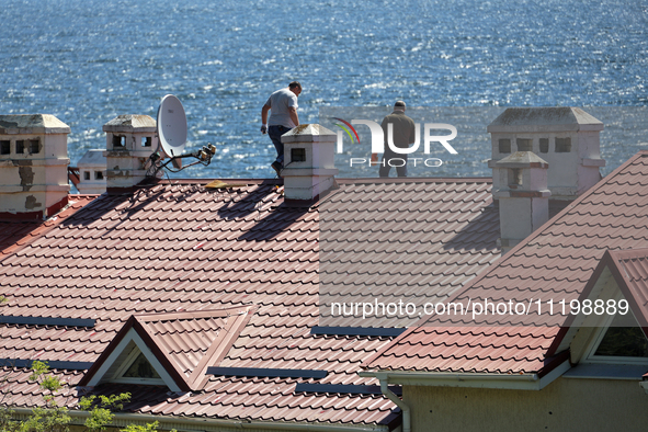 Men are checking the roof of a house after a fire caused by a Russian missile strike on the waterfront in Odesa, Ukraine, on April 30, 2024....