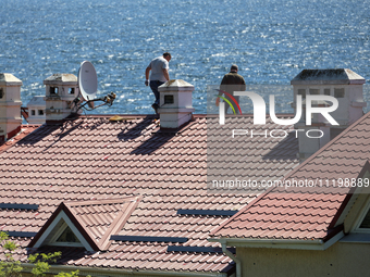 Men are checking the roof of a house after a fire caused by a Russian missile strike on the waterfront in Odesa, Ukraine, on April 30, 2024....