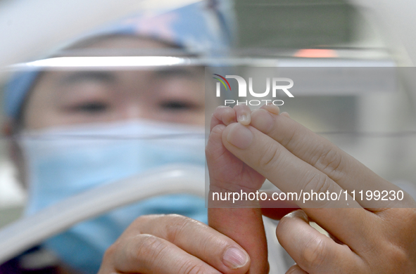 A nurse is giving a physical examination to a newborn in the neonatal intensive care unit of the No 4 Hospital in Handan, Hebei Province, No...