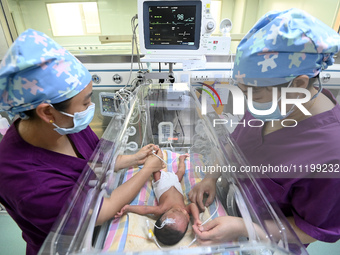 A nurse is caring for a child in the neonatal intensive care unit of the No 4 Hospital in Handan, Hebei Province, on May 1, 2024. (