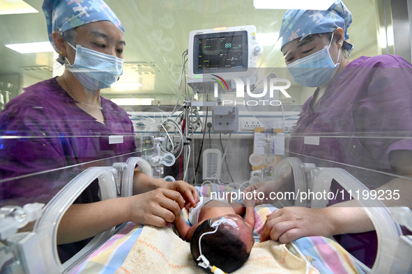 A nurse is caring for a child in the neonatal intensive care unit of the No 4 Hospital in Handan, Hebei Province, on May 1, 2024. 