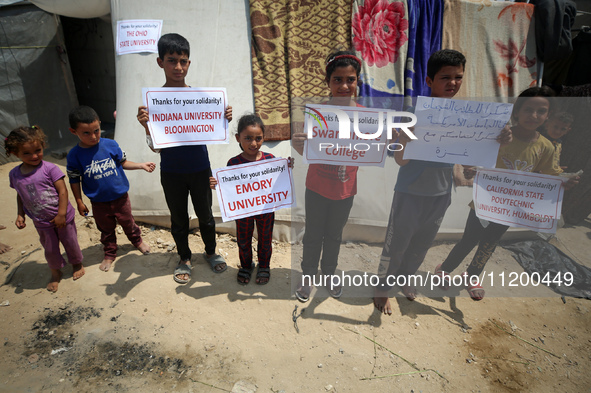 Palestinian youths are lifting placards to thank pro-Palestinian student solidarity initiatives in US and Canadian universities on their cam...