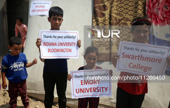 Palestinian youths are lifting placards to thank pro-Palestinian student solidarity initiatives in US and Canadian universities on their cam...