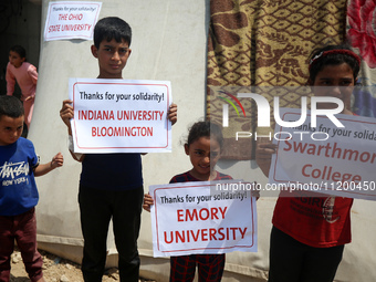 Palestinian youths are lifting placards to thank pro-Palestinian student solidarity initiatives in US and Canadian universities on their cam...