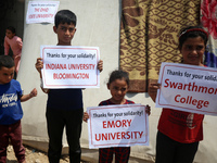 Palestinian youths are lifting placards to thank pro-Palestinian student solidarity initiatives in US and Canadian universities on their cam...