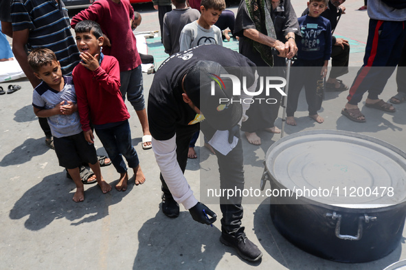 A World Central Kitchen (WCK) worker is preparing to serve meals to Palestinians at a school sheltering displaced people amid the ongoing co...