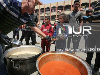 Palestinians are gathering to receive food meals cooked by World Central Kitchen (WCK) after the charity resumed operations at a school shel...