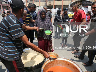 Palestinians are gathering to receive food meals cooked by World Central Kitchen (WCK) after the charity resumed operations at a school shel...