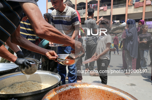 Palestinians are gathering to receive food meals cooked by World Central Kitchen (WCK) after the charity resumed operations at a school shel...