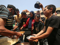 Palestinians are gathering to receive food meals cooked by World Central Kitchen (WCK) after the charity resumed operations at a school shel...