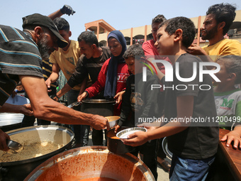 Palestinians are gathering to receive food meals cooked by World Central Kitchen (WCK) after the charity resumed operations at a school shel...