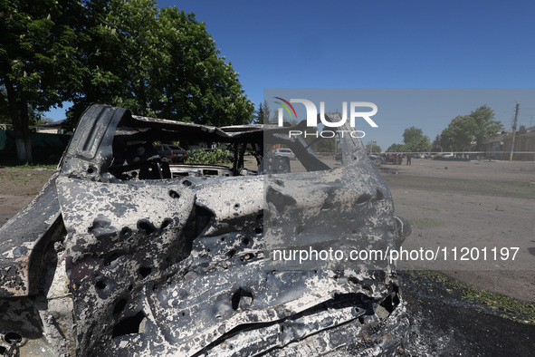 A burnt-out car is being seen in the street following a Russian strike on Zolochiv in the Kharkiv region, northeastern Ukraine, with guided...