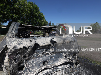 A burnt-out car is being seen in the street following a Russian strike on Zolochiv in the Kharkiv region, northeastern Ukraine, with guided...