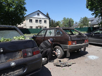 A man is crouching down by the rear wheel of a car that has been damaged by a Russian strike in Zolochiv, Ukraine, on May 1, 2024, with guid...