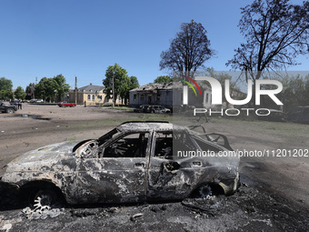 A burnt-out car is being seen in the street following a Russian strike on Zolochiv in the Kharkiv region, northeastern Ukraine, with guided...