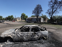 A burnt-out car is being seen in the street following a Russian strike on Zolochiv in the Kharkiv region, northeastern Ukraine, with guided...