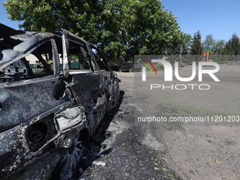 A burnt-out car is being seen in the street following a Russian strike on Zolochiv in the Kharkiv region, northeastern Ukraine, with guided...