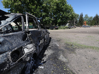 A burnt-out car is being seen in the street following a Russian strike on Zolochiv in the Kharkiv region, northeastern Ukraine, with guided...