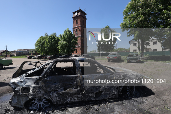 A burnt-out car is being seen in the street following a Russian strike on Zolochiv in the Kharkiv region, northeastern Ukraine, with guided...