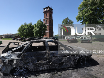 A burnt-out car is being seen in the street following a Russian strike on Zolochiv in the Kharkiv region, northeastern Ukraine, with guided...