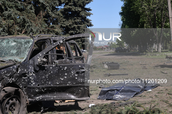 A human remains pouch containing the body of a victim is lying on the ground next to a damaged car after a Russian strike in Zolochiv, Khark...