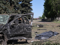 A human remains pouch containing the body of a victim is lying on the ground next to a damaged car after a Russian strike in Zolochiv, Khark...