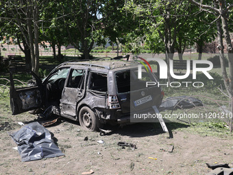 Human remains pouches containing the bodies of victims are lying on the ground next to a damaged car following a Russian strike in Zolochiv,...