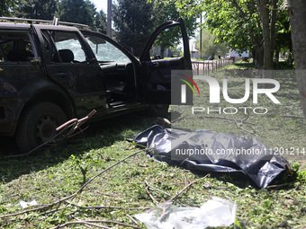 A human remains pouch containing the body of a victim is lying on the ground next to a damaged car after a Russian strike in Zolochiv, Khark...