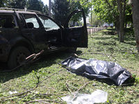 A human remains pouch containing the body of a victim is lying on the ground next to a damaged car after a Russian strike in Zolochiv, Khark...