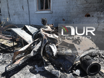 A burnt-out car is being seen in the street following a Russian strike on Zolochiv in the Kharkiv region, northeastern Ukraine, with guided...