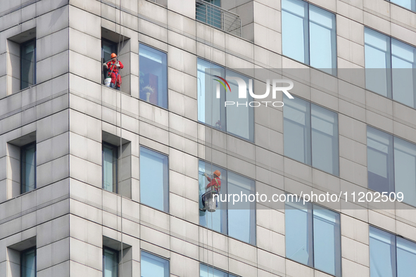 Workers are cleaning the windows on each floor of a high-rise building in the Chaoyang district of Beijing, China, on May 1, 2024. In Beijin...