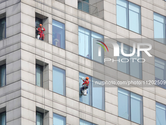 Workers are cleaning the windows on each floor of a high-rise building in the Chaoyang district of Beijing, China, on May 1, 2024. In Beijin...