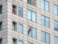 Workers are cleaning the windows on each floor of a high-rise building in the Chaoyang district of Beijing, China, on May 1, 2024. In Beijin...