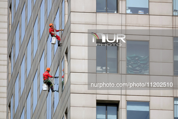 Workers are cleaning the windows on each floor of a high-rise building in the Chaoyang district of Beijing, China, on May 1, 2024. In Beijin...