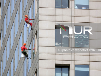 Workers are cleaning the windows on each floor of a high-rise building in the Chaoyang district of Beijing, China, on May 1, 2024. In Beijin...