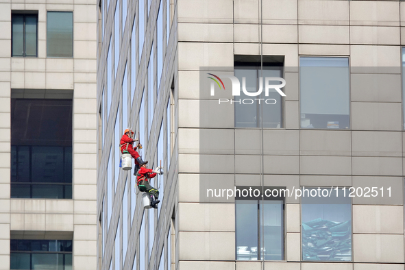 Workers are cleaning the windows on each floor of a high-rise building in the Chaoyang district of Beijing, China, on May 1, 2024. In Beijin...