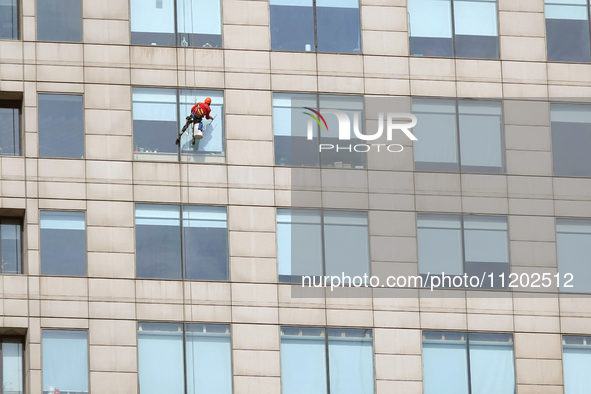 Workers are cleaning the windows on each floor of a high-rise building in the Chaoyang district of Beijing, China, on May 1, 2024. In Beijin...