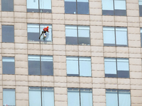 Workers are cleaning the windows on each floor of a high-rise building in the Chaoyang district of Beijing, China, on May 1, 2024. In Beijin...