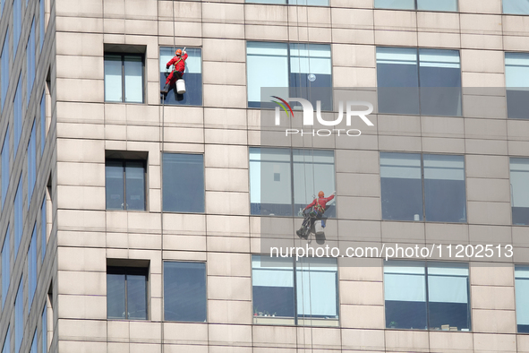 Workers are cleaning the windows on each floor of a high-rise building in the Chaoyang district of Beijing, China, on May 1, 2024. In Beijin...