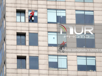 Workers are cleaning the windows on each floor of a high-rise building in the Chaoyang district of Beijing, China, on May 1, 2024. In Beijin...