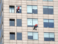 Workers are cleaning the windows on each floor of a high-rise building in the Chaoyang district of Beijing, China, on May 1, 2024. In Beijin...