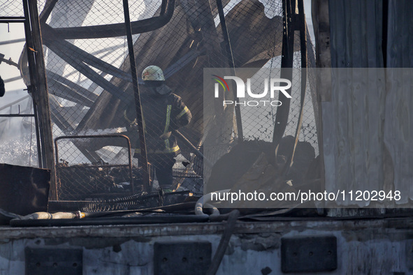 A firefighter is putting out a fire at a Nova Poshta depot and cargo branch in Odesa, Ukraine, on May 2, 2024, which was damaged by a Russia...