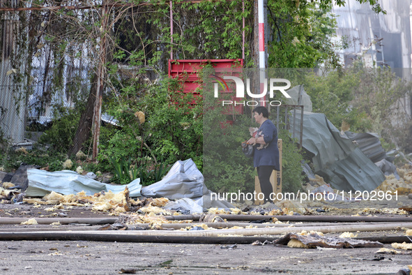 A woman is holding a dog and standing among the rubble near a Nova Poshta depot and cargo branch that has been damaged by a Russian ballisti...